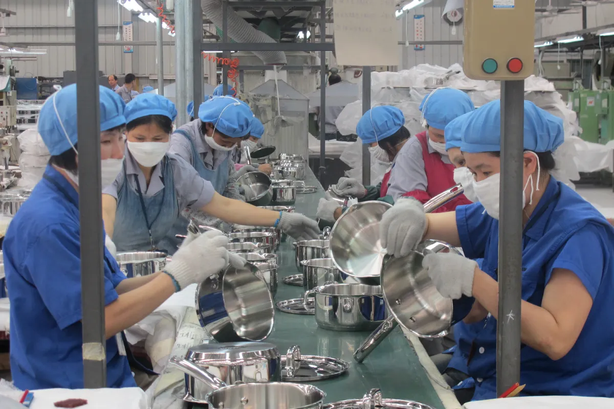 Workers on stainless steel cookware OEM assembly line in manufacturing factory